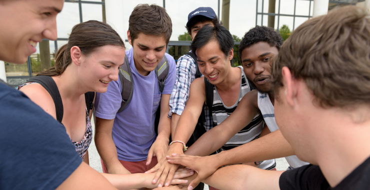 group of students putting their hands in a circle