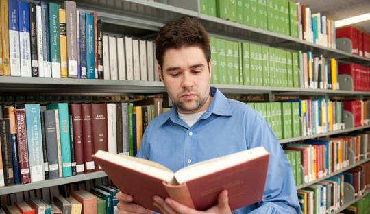 Young man with book in library