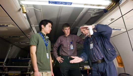 3 men in airplane bay discussing