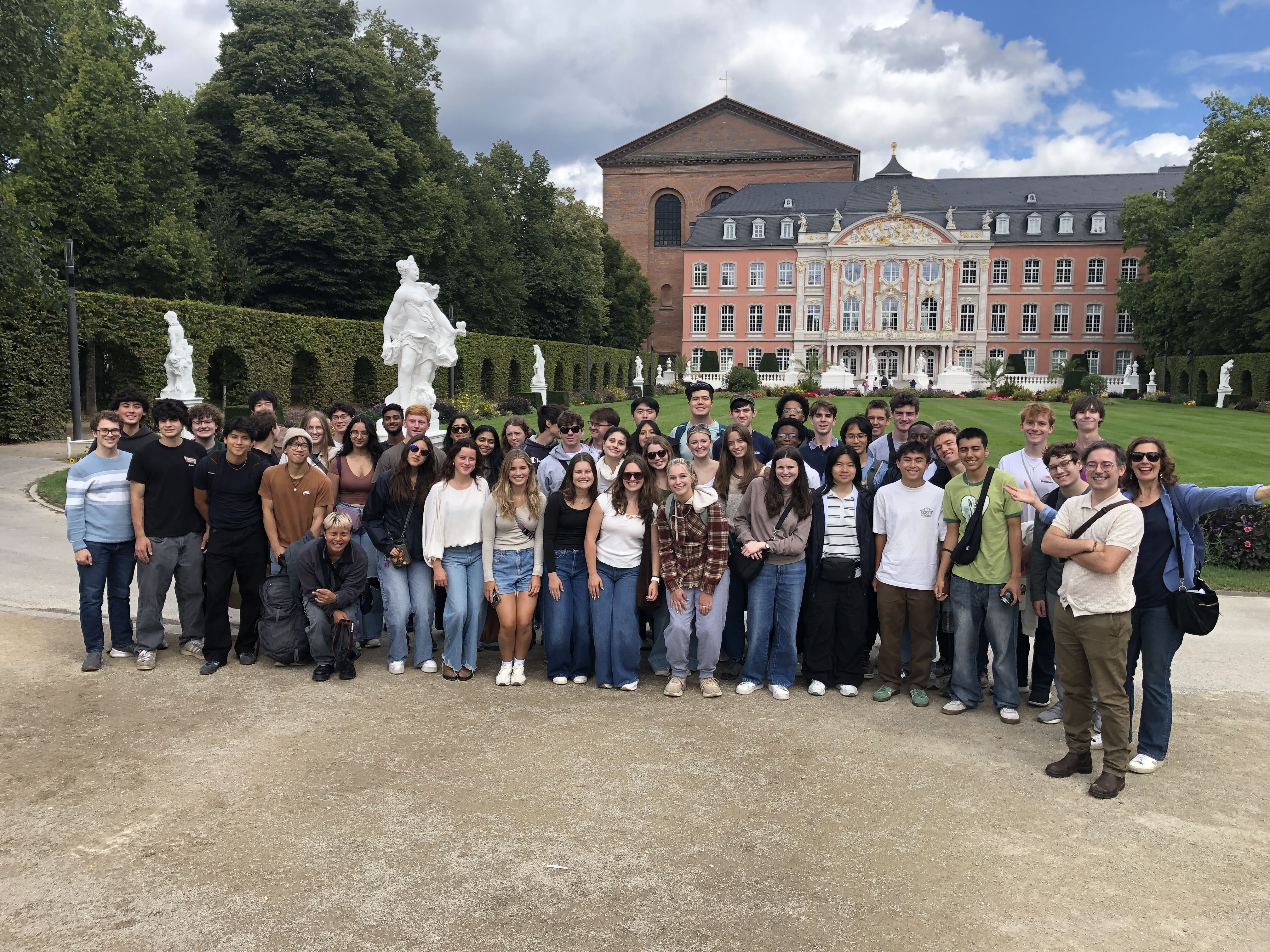 Large group of first year students visits Trier with faculty and stands in front of historic building