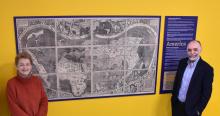 Sonia Serafin and Abdallah Ougazzaden pose by a copy of the famous world map&nbsp;by Martin Waldseemüller, hanging in Georgia Tech-Lorraine's student lounge.